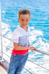 A boy standing on a ship with his hair blowing in the wind