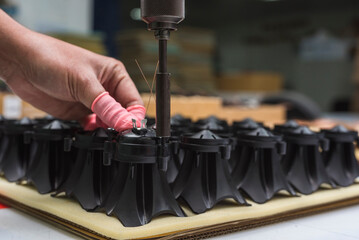 A factory worker using an electric screwdriver to assemble piezoelectric tweeters. Niche and...