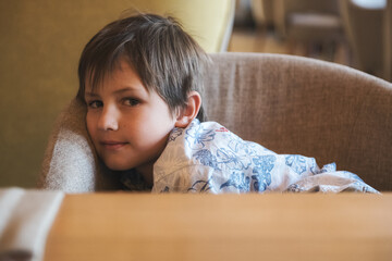 A boy sitting on a sofa and looking into the camera