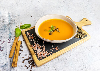 Pumpkin traditional soup with creamy  texture on gray textured background . Top view 