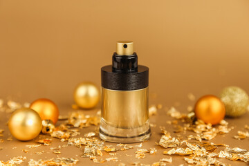 Obraz na płótnie Canvas Mockup gold black spray perfume bottle, gold christmas balls and paper firecracker pieces on golden background. Glass perfume bottle for branding and label. Eau de toilette. Front view.