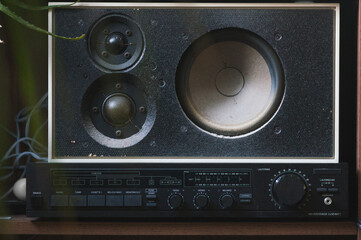 old analog hifi audio stereo in a shelf.  old vintage loudspeaker and amplifier of a stereo in a wooden shelf with plant