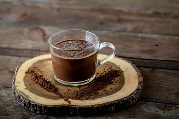 High angle shot of dark chocolate milkshake in a  glass mug on wooden surface