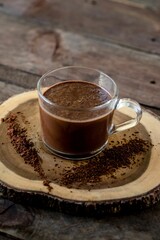 Vertical high angle shot of dark chocolate milkshake in a  glass mug on wooden surface