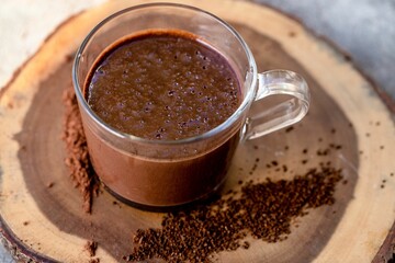 High angle shot of dark chocolate milkshake in a  glass mug on wooden surface