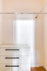 Trendy white empty dressing utility room with shelves and hangers.