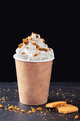 Paper cup with hot drink with whipped cream on dark background. Recycling and eco friendly concept.