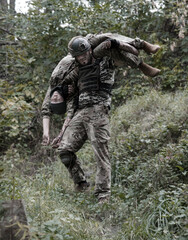 Fototapeta premium The commander carries a wounded soldier