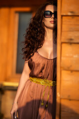 beautiful woman with long hair posing fashion near a wooden cabin