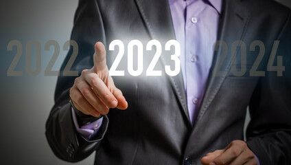 Finger pressing blue start 2023 button on virtual interface on gray background with copy space for text. Concept of new year. Businessman pressing 2023 start up business. Beginning of New Year 2023.