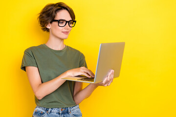 Photo of positive focused nice woman with bob hairdo dressed khaki t-shirt writing email hold laptop isolated on yellow color background