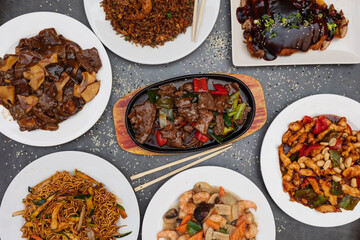 Assorted Chinese food. Chinese noodles, fried rice, dumplings, roast duck, yakisoba. Famous Chinese cuisine dishes on the table. Top view. Chinese restaurant concept. Asian style banquet