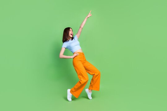 Full size photo of crazy positive girl raise hand point finger enjoy dancing isolated on green color background