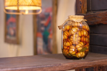 pickled garlic in a large glass jar on a wooden shelf. Tasty pickled garlic