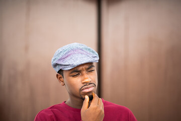 Fototapeta na wymiar Young black man with cap looking away and thinking
