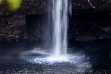 Fototapeta na wymiar close-up of high waterfall plummeting into pool of freshwater below cave