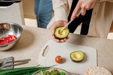 Close up of woman hands cutting fresh avocado in modern kitchen. Nutrition And Diet. Healthy food concept. Ingredients for smoothies