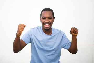 Fototapeta premium Excited young african man with arms raised against white background