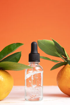 Concept of natural organic orange essential oil for skin face and body health care. Moisturizing, aromatherapy, detox treatment, anti-stress effect. Fresh fruit, green leaves, orange background