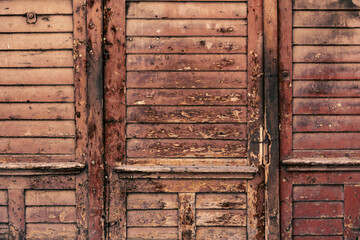 Old weathered and damaged maroon wood of a door or rustic entrance
