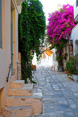 Fototapeta na wymiar One of the charms of the Greek islands of the Cyclades, in the heart of the Aegean Sea, are the narrow streets lined with white houses with their cobbled stairs and their small flowered balconies