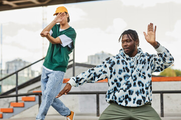 Portrait of two young men dancing outdoors in urban area and wearing street style clothes