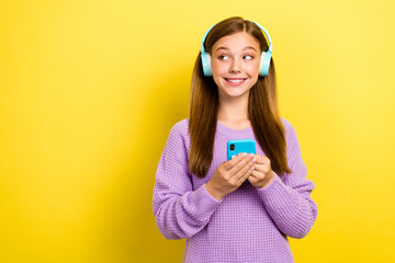 Portrait photo of teenager girl wear warm sweatshirt hold phone wireless headphones listen ebook...