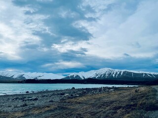 Scenic shot of a snowy mountain range behind the frozen sea under the clouded sky