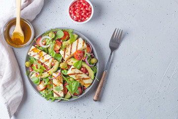 Salad with fried Halloumi cheese, cherry tomatoes, arugula and pomegranate seeds. healthy food. copy space