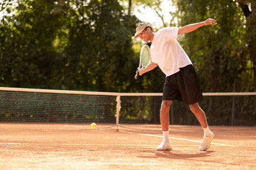 Young man in white tshirt with a tennis racket in hands