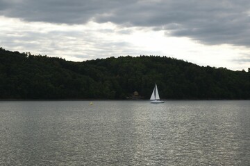 High-angle of a boat flowing in the lake at sunset with mountain silhouettes, cloudy sky background