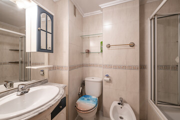 Bathroom with white porcelain taps, white marble top, mirror embedded in wooden cabinet and shower with folding doors