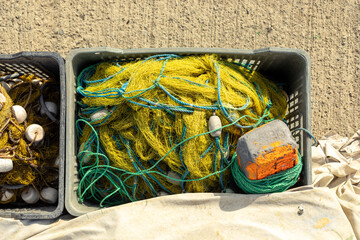 Yellow fishing net with the green rope in the grey plastic box.