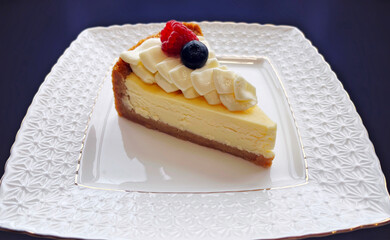 Classic plain New York Cheesecake slice on a white plate. Piece of cheesecake with fresh...