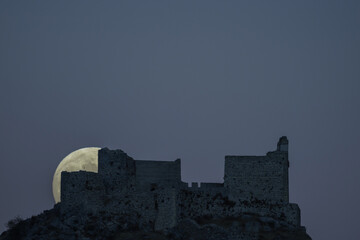Obraz premium photographing the full moon as it rises behind a castle