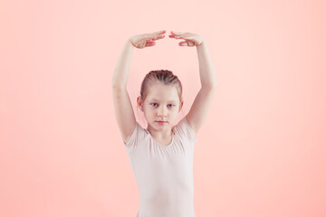 little ballet dancer girl in tutu posing with arms raised over pink background - stock photography