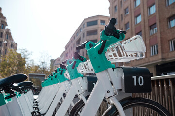 A row of e-bikes are parked at dock station in a street city.