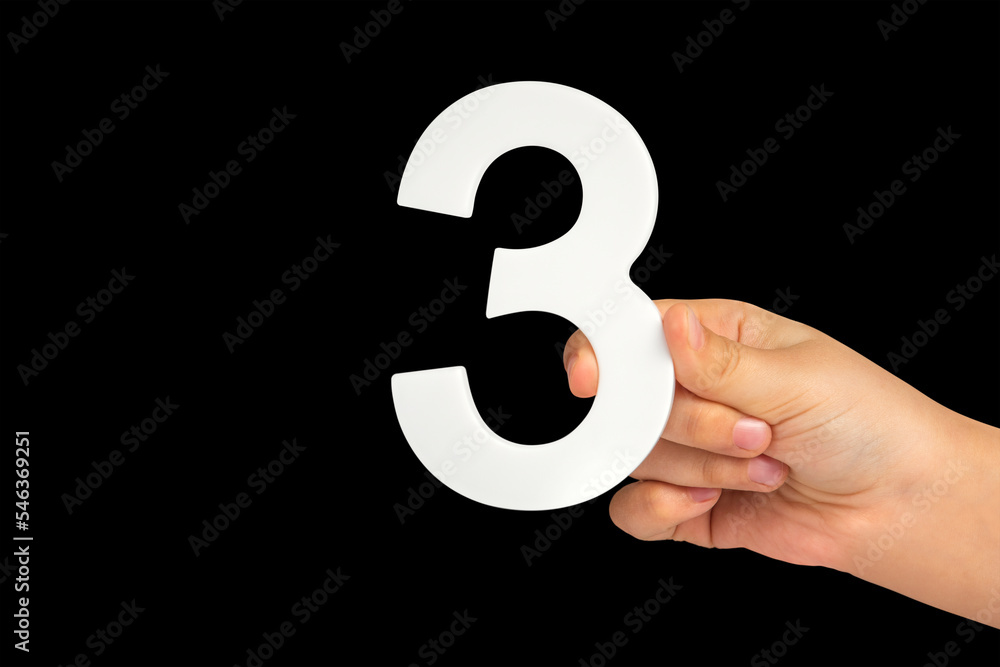 Poster number three in hand isolated on black background. number three in a child's hand on a black backgro