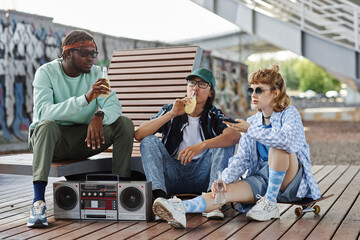 Diverse group of young people hanging out in urban city setting with boombox