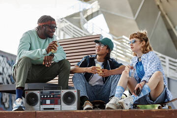 Full length portrait diverse group of young people hanging out with boombox in urban city setting