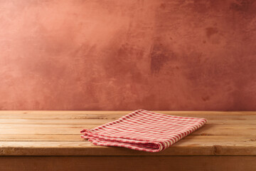 Red checked tablecloth on wooden table over rustic wall  background. Kitchen interior mock up for...
