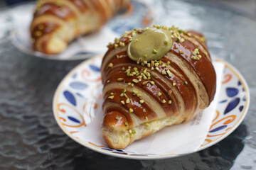 Obraz na płótnie Canvas Big tasty and delicious croissant with pistachio cream filling on plate