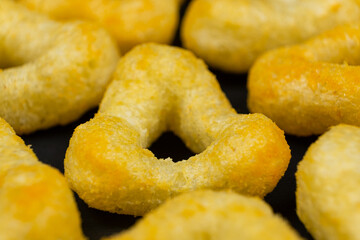 Delicious crispy corn chips triangular shape with spices on a black background.