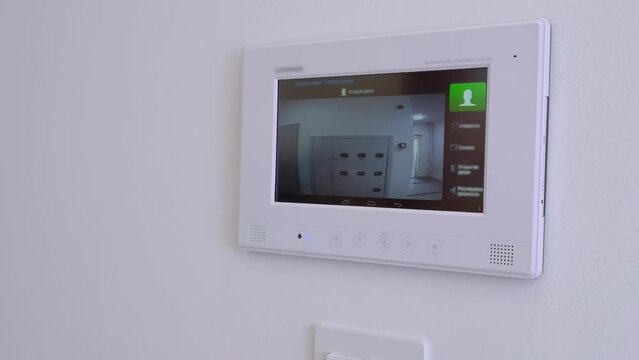 Smart Home, A Man Answers A Call To The Intercom, Side View. Monitoring, Unlock. Apartment Video Intercom System, Video Doorbell With Camera And Monitor.