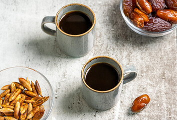 Healthy date seed coffee in two cups, dates fruits and seeds on grey background. Top view