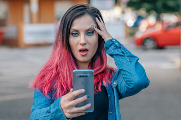 girl with dyed red hair in shock looking at mobile phone