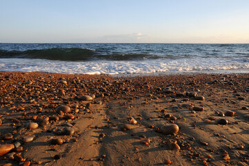 close up of pebbles on a beach with waves lapping the shore in the disctance