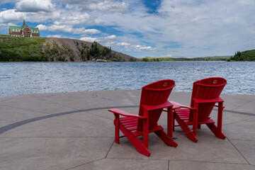 Red adirondack chairs and the Prince of Wales Hotel at Waterton Lakes National Park, in Canada during summer