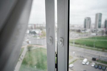 Window with plastic frame and white curtain is open. Wind blows to open window frame for room ventilation.