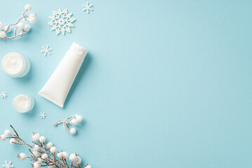 Winter season skin care cosmetics concept. Top view photo of jars of cream white tube snowflakes and plant branches in hoarfrost on isolated pastel blue background with copyspace
